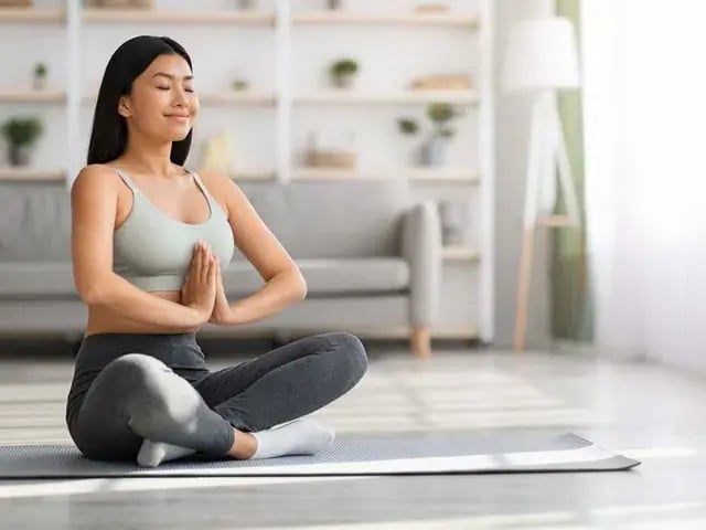 Pessoa meditando na sala de casa